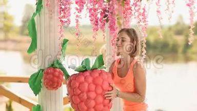 花艺女孩用一个大人造草莓装饰一个结婚拱门